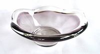 Top angled view showing scalloped edges and purple tint of glass trinket dish.