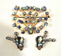 Front view of aurora borealis crystal brooch and clip-on earrings set showing blue crystals in gold-tone metal.