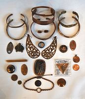 All items laid out flat on white background showing full assortment of copper jewelry, coins, and Vulcan Association token with certificate and packaging