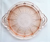 Full view of the cranberry pressed glass plate showing overall shape, handles, and floral pattern