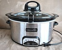 Front view of Crock-Pot slow cooker showing stainless steel exterior, black plastic handles, digital control panel, and glass lid with stirring attachment handle.