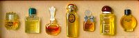 Photo showing seven mini perfume bottles of different styles and colors arranged side-by-side.