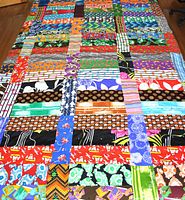 Full view of colorful patchwork quilt showing multiple fabric patterns and colors sewn together in rows and columns.