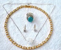 Full lot shown on white textured fabric background including gold tone rhinestone necklace, Swarovski crystal bead pendant necklace, turquoise cabochon ring, and crystal earrings.