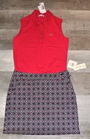 Full view of the sleeveless red Lacoste shirt paired with the geometric pattern stretch skort laid flat on the floor showing both items and tags attached.