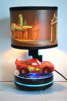 Full view of the Lightning McQueen lamp lit and displaying the lampshade with night scene.