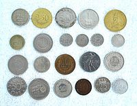 Top view of 22 vintage foreign coins arranged in rows showing fronts with denominations and symbols