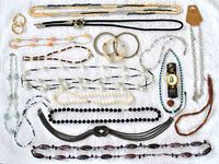 All costume jewelry items laid out displaying necklaces, bracelets, a bolo tie, and a watch for a full overview.