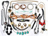 Full assortment of costume jewelry laid flat on white background showing necklaces, bracelets, earrings, watches, and brooch.