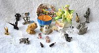 Various small dollhouse miniatures including animals, decorative pieces, and figurines set on white fabric.