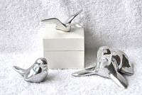 Photo showing three polished metal figurines: a bird, a seal, and a flying goose sitting on a box