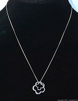 Sterling silver necklace with double flower pendant on black background showing full chain and pendant.