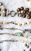 Close-up of clasps and pearls showing variety of colors and styles, including brown and white pearls, and clasp types.