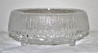 Side view of the clear textured glass footed dish showing vertical ridged pattern and transparent finish.