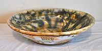 Side view of the hand-glazed ceramic bowl showing the mottled earth-tone interior with glossy finish.