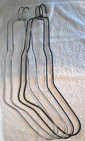 Four metal sock stretchers including two for smaller feet and two for larger feet hung on a white towel.
