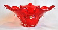 Front view of red Murano glass bowl showing wavy rim and clear glass accents on the sides.
