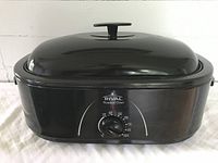 Front view of black Rival electric roaster oven with lid closed, displaying brand label and temperature dial