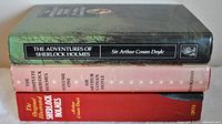 Stack view of the three vintage Sherlock Holmes hardcover books showing titles and authors on spine and front cover.