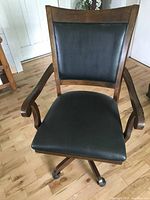 Front angle of chair showing leather seat, backrest, wooden frame and armrests.