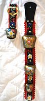 Front view of the two Swiss bell sets with detailed painted designs on the bells and red felt backing