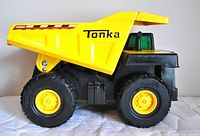 Side view of Tonka dump truck showing yellow dump bed with '4000' and Tonka logo, black chassis, yellow wheels, and simulated large tires with Tonka on tire sidewall.