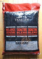 Full view of sealed 9kg bag of Traeger Signature Blend premium hardwood pellets in red and black bag