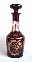 Full view of red ruby crystal decanter with wide stopper, showing clear cut pattern on body and neck.