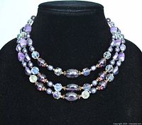 Front view of the 3-strand vintage costume jewelry necklace showing layering with purple and clear AB faceted beads, simulated pearls, seed beads, and brass spacers.