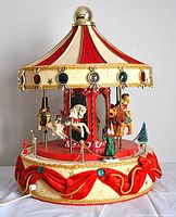 Full view of the vintage Christmas carousel featuring a striped canopy, jewel embellishments, and decorative base with fabric garlands.