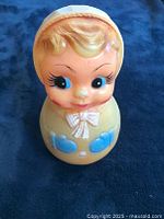 Full view of vintage roly poly doll toy with painted toddler face, hat, and colorful outfit details