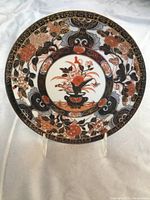 Top view of the plate showing the detailed blue and orange floral design with gold highlights and central vase motif.