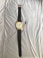 Full view of the large vintage Sabre wristwatch laid out on fabric, showing the entire length including the black leather strap and brass casing.