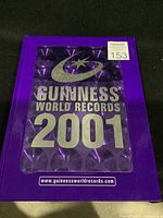 Front cover of the 2001 Guinness World Records book showing purple cover with silver embossed title and website address.