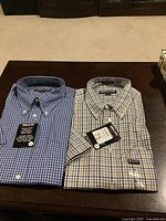 Photo of two folded men's Kirkland large cotton twill shirts, showing tags and patterns.