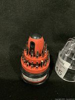 Closed view of 30-1 mini screwdriver set with bits arranged around the handle in red and black plastic holder.