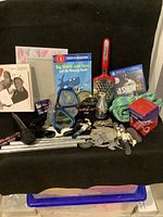 Full lot view showing multiple items including books, water goggles, PS4 game, cheese cutters, rope, wind chimes, microphone, and CD collection.