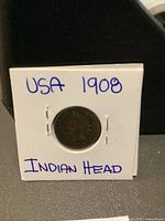 Obverse of 1908 American Indian Head Penny showing the profile of Lady Liberty with Native American headdress and year 1908 in a white cardboard coin flip holder.