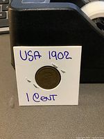 Front view of the 1902 USA Indian Head penny mounted in a white coin holder.