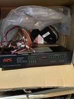 Box contents showing black APC battery management system unit with wiring harness inside plastic bag