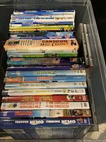 Top view of a collection of children DVDs arranged in a box including titles like 35 Cartoon Classics, Bambi, Aladdin, Shrek 2, Khumba, Despicable Me 2, Finding Nemo, Zariland