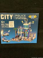Front view of building blocks box showing completed police station with vehicles and piece count