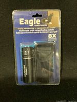 Front view of Eagle Series Golf Scope with Rangefinder 8X in original sealed blister packaging showing product and case.