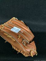 Handcrafted Eaton baseball glove showing outer hand and fingers with tan leather and yellow lacing, laid on black background.
