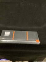 Side view of the Fiskars SureCut Paper Trimmer showing the gray base with orange markings and ruler.