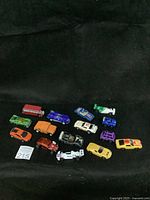 Array of 15 toy cars in multiple colors and styles against black background.
