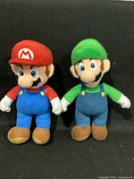 Photo of two plush toys, Mario and Luigi, standing side by side, showing full front view and details.