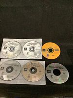 Top view of six PlayStation game discs including two Final Fantasy IX discs, two Final Fantasy Tactics discs, Beyond the Beyond, and Breath of Fire III.