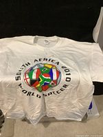 White XL t-shirt featuring a multi-flag soccer ball design and text 'South Africa 2010 World Soccer'. New with original Gildan tag.