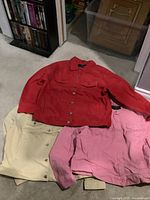 Red, beige, and pink AZUR jean jackets laid out together on floor showing front button closure and pockets.